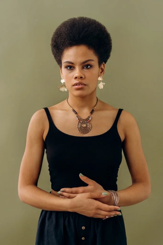 Rostro ovalado con corte afro redondeado.